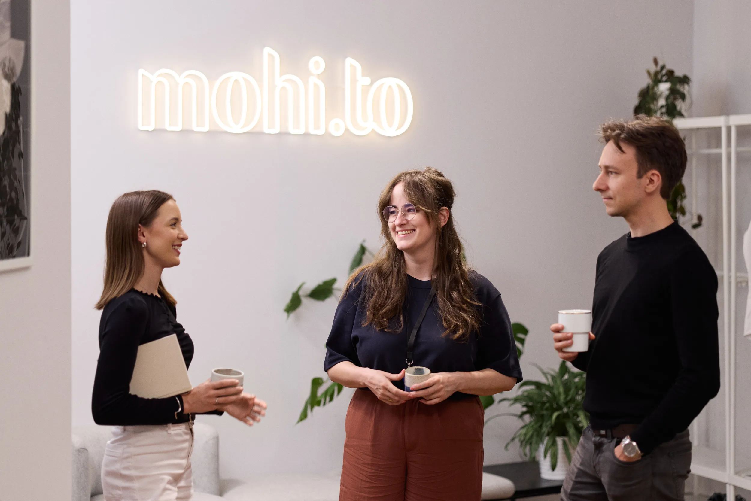 Team members chatting by the mohi.to office sign