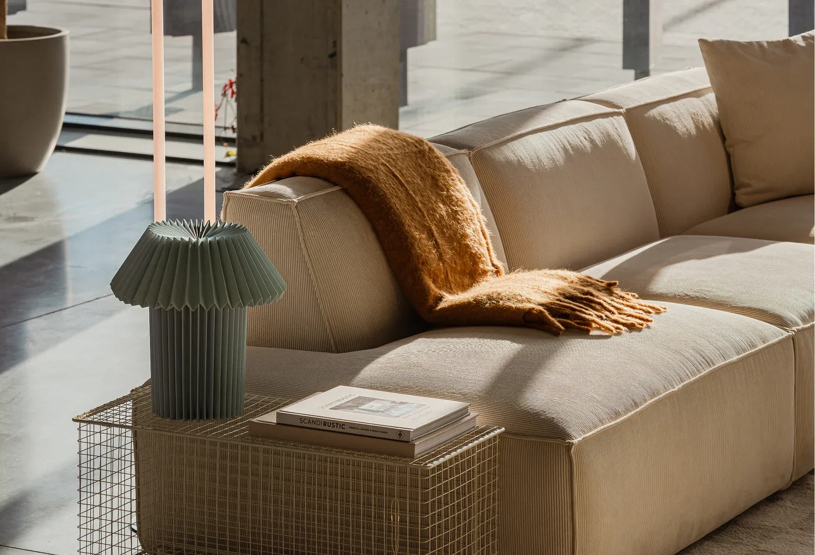 Sunlit living room with a beige modular Optisofa sofa, a rust-orange throw and a green pleated table lamp